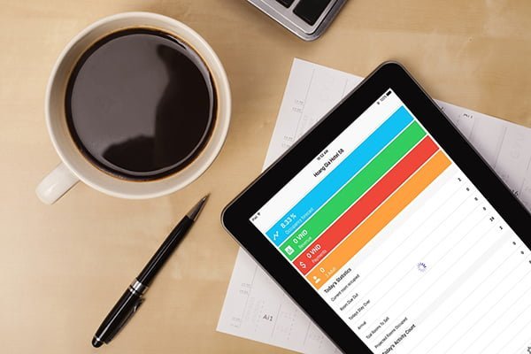 Workplace with tablet pc showing charts and a cup of coffee on a wooden work table close-up