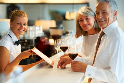 Smiling female bartender and mature couple at the bar counter